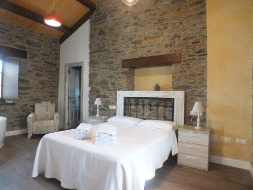 a bedroom with a large bed and a stone wall at Apartamentos Puerta del Castro in Coaña
