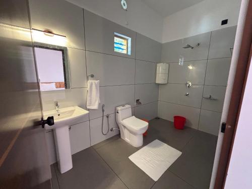 a white bathroom with a toilet and a sink at Tranquil Waves Marari in Mararikulam