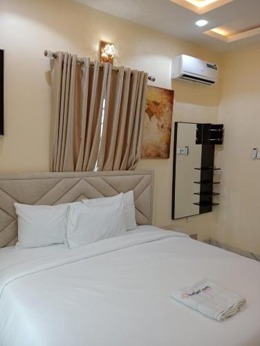 a bedroom with a white bed and a window at Pinefield Courts Apartment in Akure