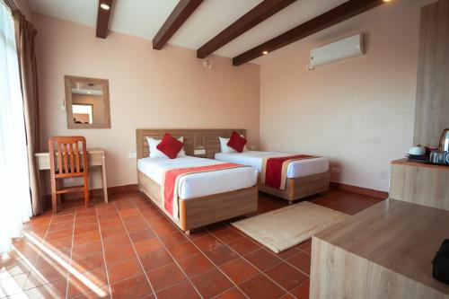 a bedroom with two beds and a table and a chair at Gateway Himalaya Resort in Ghanpokhara