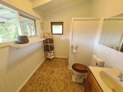 a bathroom with a toilet and a sink and a window at Foster - Nature Retreat - Nippards Nature Cottage in Boolarong