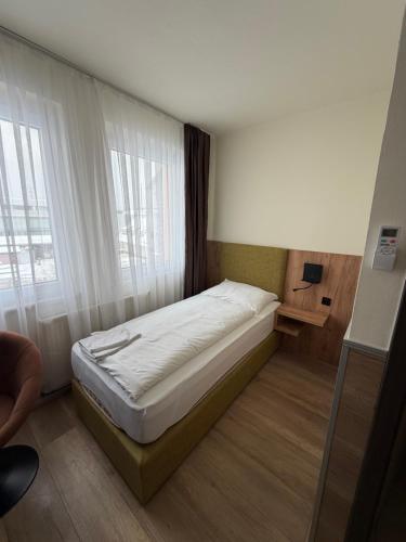 a bed in a small room with a window at Turm Inn 24H Self Check In By H&H Hotels in Linz