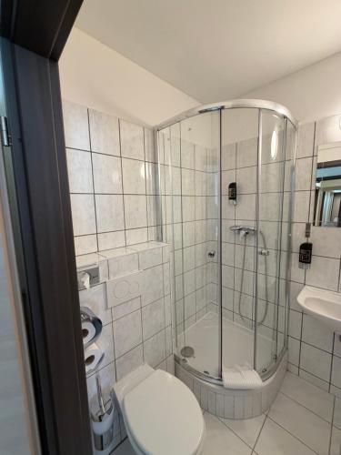 a bathroom with a shower and a toilet and a sink at Turm Inn 24H Self Check In By H&H Hotels in Linz