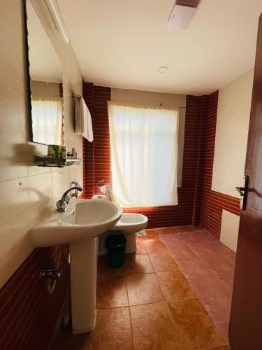 a bathroom with a sink and a toilet and a window at Gateway Himalaya Resort in Ghanpokhara