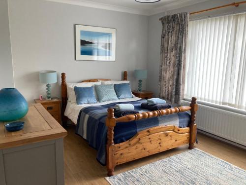 a bedroom with a bed with blue pillows at Awel Deg in Pembrokeshire