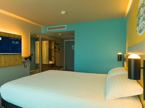 a bedroom with a large white bed with a blue wall at B&B HOTEL Warrington in Warrington