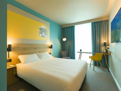 a hotel room with a large bed and a desk at B&B HOTEL Warrington in Warrington