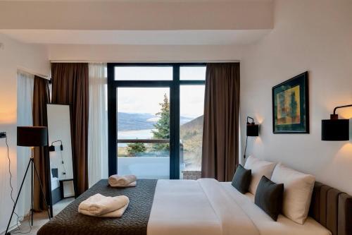 a bedroom with a large bed with a large window at LAKEVIEW Hotel & Apartments in Mavrovo