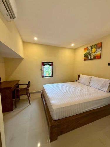 a bedroom with a bed and a desk in it at Alena in Nusa Dua