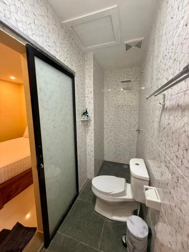 a white bathroom with a toilet and a bed at Alena in Nusa Dua