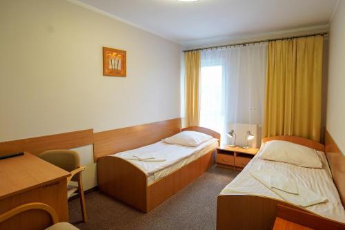 a hotel room with two beds and a desk at Hotel Stadion in Kielce