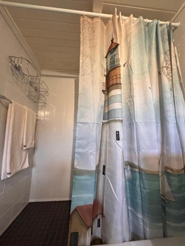 a shower curtain with a lighthouse painted on it in a bathroom at Lüttje Koje - Ferienhaus direkt am Deich und dem Meer dahinter in Norden