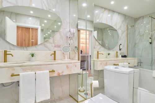 a bathroom with a sink and a toilet and a mirror at Hotel de Ilhavo Plaza & Spa in Ílhavo
