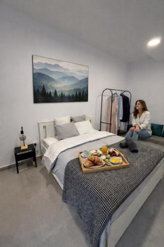 a woman sitting on a bed with a tray of food on it at Limassol center Soul in Limassol