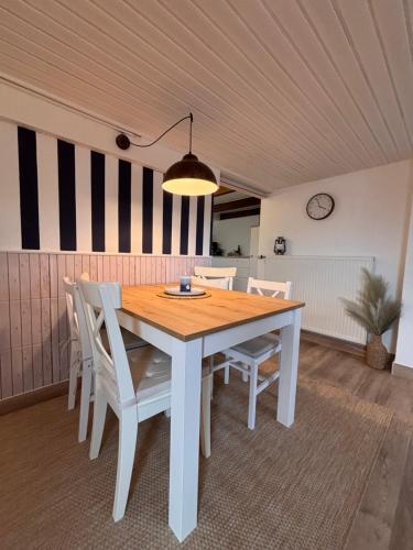 a dining room with a wooden table and chairs at Lüttje Koje - Ferienhaus direkt am Deich und dem Meer dahinter in Norden