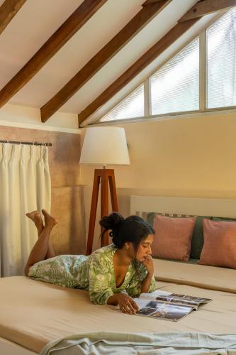 a woman laying on a bed reading a magazine at Tool House - Great Estate Stay for Remote Work in Siddapur