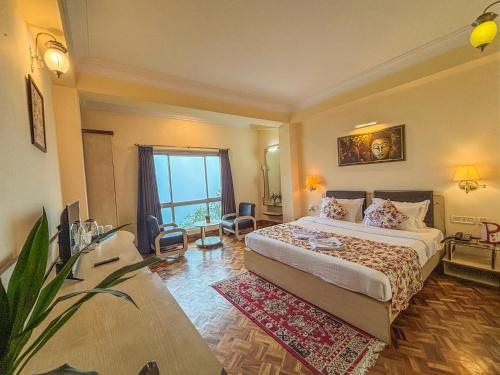 a hotel room with a bed and a large window at Rare Himalayas De Regency Pelling in Pelling