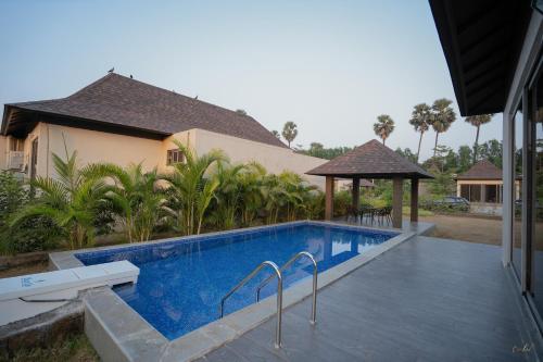 a swimming pool in front of a house at Daksh The Nirvana Retreat in Vitoj