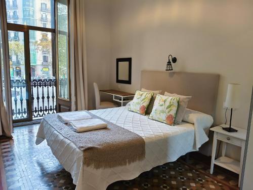a bedroom with a white bed with a balcony at Casa Consell Bailen, Guest House in Barcelona