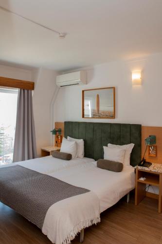 a bedroom with a large bed with a green headboard at WOT Ericeira in Ericeira
