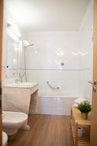 a white bathroom with a tub and a sink at WOT Ericeira in Ericeira