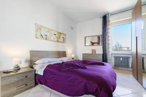 ein Schlafzimmer mit einem lila Bett und einem großen Fenster in der Unterkunft Casa Sofìa in Turin