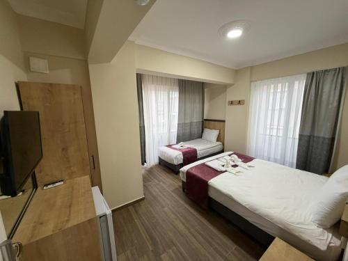 a hotel room with two beds and a flat screen tv at Alpaslan Otel Pansiyon in Antalya
