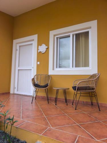 two chairs and a table in front of a door at Maio Sweet Tartaruga in Vila do Porto