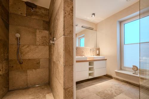 a bathroom with a shower and a sink and a window at Doppelhaushälfte Strandgut 4 in Sylt