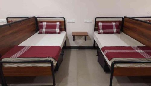 two beds in a room with a table between them at Sukhnidras Dormitory in Hyderabad