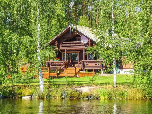 a log cabin in the woods next to a lake at Holiday Home Rantalaukka by Interhome in Haapiala