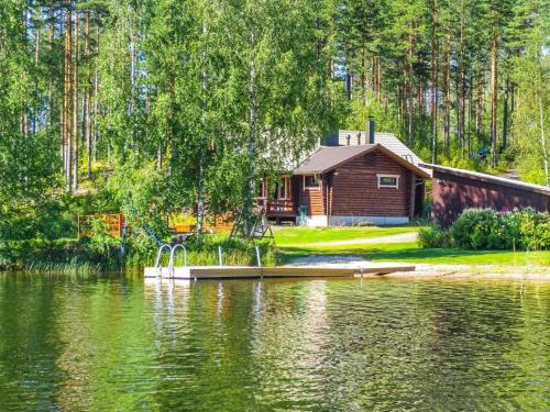 a cabin next to a lake with a house at Holiday Home Rantalaukka by Interhome in Haapiala