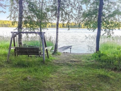 a park bench sitting next to a body of water at Holiday Home Kuusiranta by Interhome in Harjula