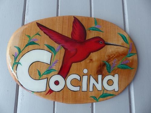 a wooden sign with a red bird on it at Hotel El Colibri Rojo - Cabinas - Le Colibri Rouge in Cahuita