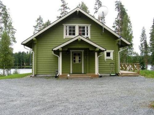a small green house with a porch on a lot at Holiday Home Villa helmi by Interhome in Holiseva