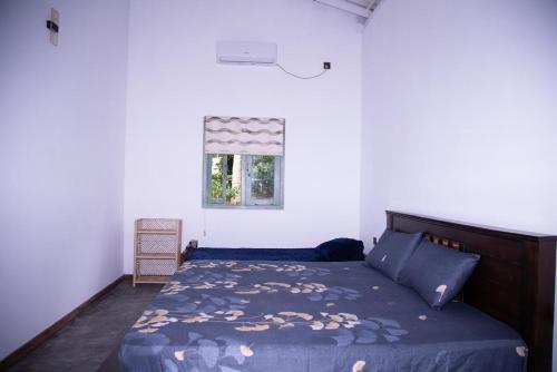 a bedroom with a bed with a blue comforter and a window at LEONS Stay in Galle