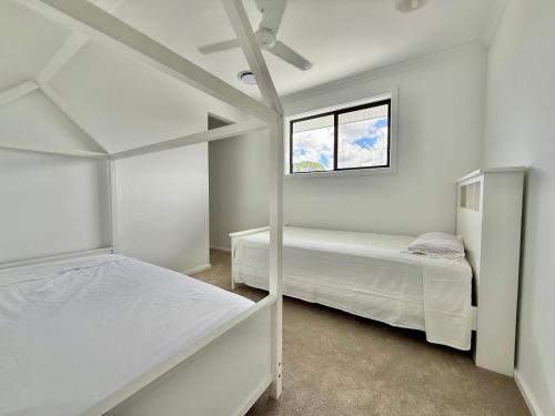 two beds in a white room with a window at The Calypso Bay in Jacobs Well