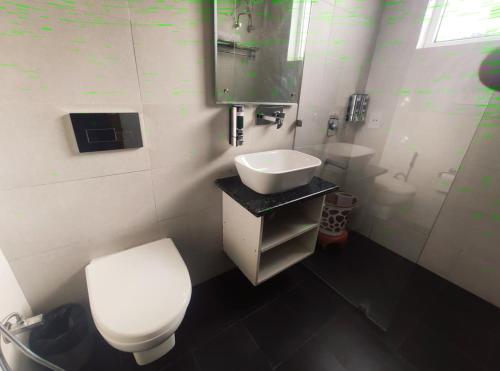 a bathroom with a white toilet and a sink at Surwel Hotel and Resort in Mussoorie