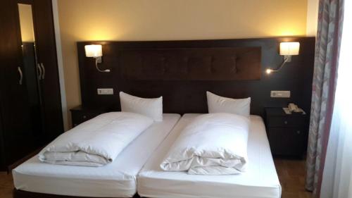 a bed with white sheets and pillows on it at Hotel Starkenburger Hof in Heppenheim an der Bergstrasse