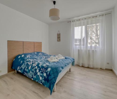 a bedroom with a bed with a blue comforter and a window at Les Peupliers Appart de Charme in Compiègne