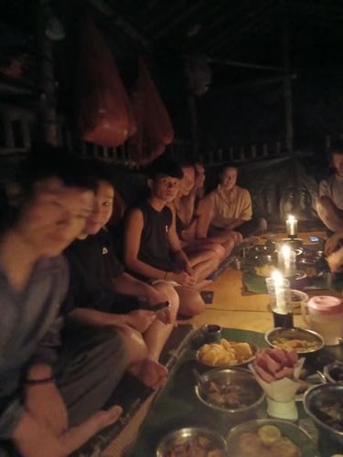 a group of people sitting around a table with food at Orangutan Inn in Bukit Lawang