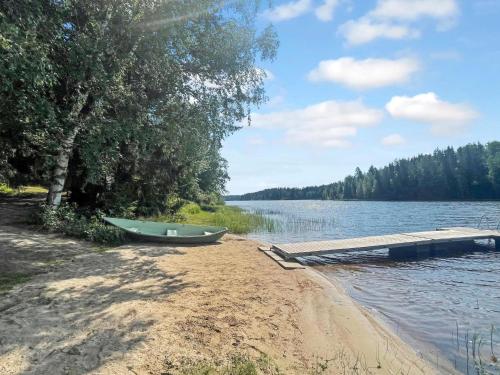 a boat on the shore of a lake with a dock at Holiday Home Hellinki by Interhome in Vaskivesi