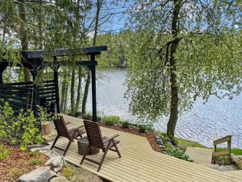 two chairs sitting on a wooden deck next to a lake at Holiday Home Hellinki by Interhome in Vaskivesi