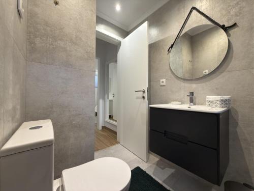 a bathroom with a white toilet and a mirror at Casinhas do Penedo in Canelas