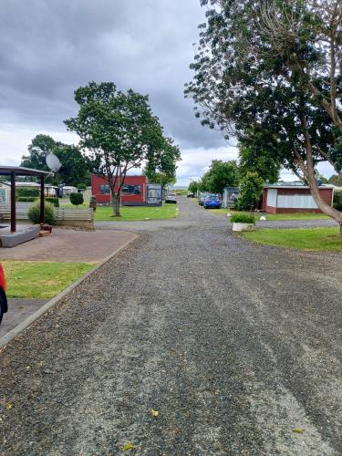 a gravel road with trees and buildings in the distance at Coro Coast getaway in Te Puru