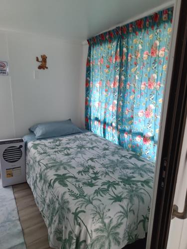 a small bedroom with a bed with a curtain at Coro Coast getaway in Te Puru