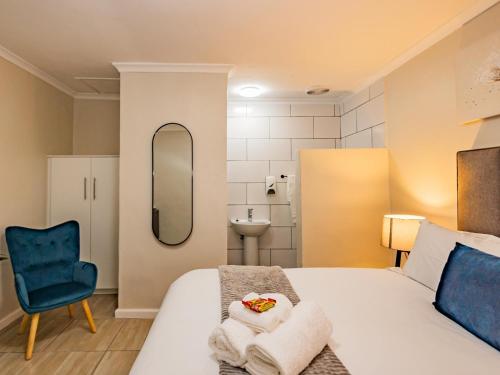 a bedroom with a bed and a mirror and a chair at Olive Grove Bed & Breakfast in Kraaifontein