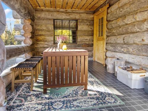 a porch of a log cabin with a bench and a tub at Holiday Home Äkäsranta by Interhome in Äkäsjoensuu