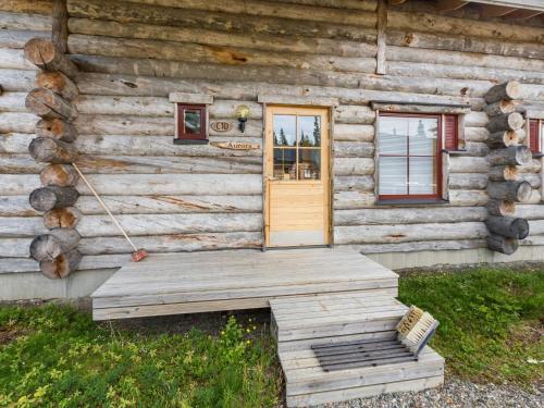 a wooden cabin with a door and a bench outside at Holiday Home Sapara c10 by Interhome in Äkäslompolo