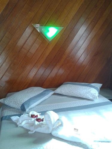 a bed with a green light on a wooden wall at Pousada Recanto das Águas in Lumiar